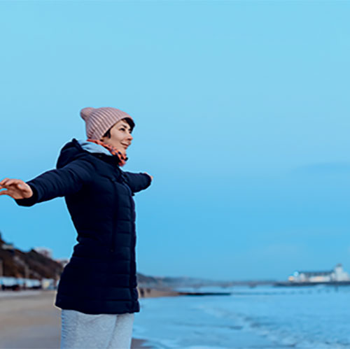 femme libre devant la mer avec les bras écartés