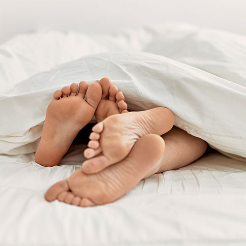 pieds d'un couple sous la couette