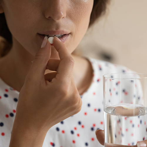 Femme prenant un probiotique avec un verre d'eau